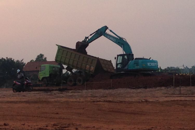 Sebuah ekskavator menurunkan tanah yang diangkut truk, Senin (22/5/2017). Tanah tersebut digunakan untuk menyusun pondasi struktur Jalan Tol Batang-Semarang.