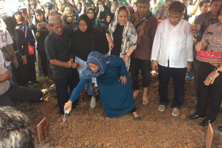 Ibunda Italia Chandra Kirana Putri (22) menyirami kubur mendiang anaknya usai dimakamkan di TPU Selapajang, Kota Tangerang, Selasa (13/6/2017). Ita meninggal dunia usai ditembak pelaku curanmor di rumahnya pada Senin (12/6/2017) siang.
