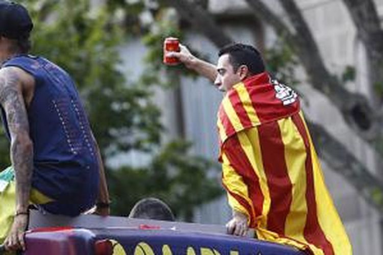 Xavi Hernandez (kanan) terlihat tengah menikmati parade gelar juara terakhirnya sebagai pemain Barcelona, Minggu (7/6/2015). 