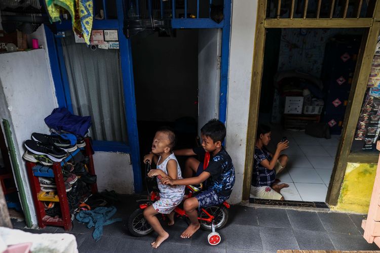 Muhammad Fauhad (10) bermain sepeda bersama adiknya, Azmi Ramadan dirumahnya di Gang Nusa Indah 1, RT 04/03, Ciracas, Jakarta Timur, Rabu (9/6/2021). Azmi Ramadan terlahir dengan satu ginjal dan kondisi wajah yang tidak seperti anak pada umumnya yaitu bagian mata yang tertutup, bibir sumbing, dan tidak memiliki rongga mulut.