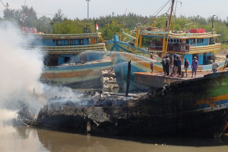 Petugas bersama warga berusaha memadamkan api dalam peristiwa kebakaran yang menghanguskan belasan kapal di sebuah galangan kapal di Jalan Bali, Kota Tegal, Jawa Tengah, Rabu (17/11/2021). 