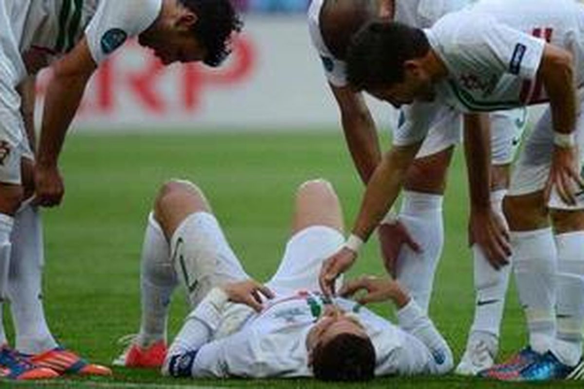 Bomber Portugal Cristiano Ronaldo (tengah) sedang berbaring di lapangan dan rekan-rekannya berusaha menolongnya bangkit kembali saat melawan Denmark dalam laga lanjutan penyisihan Grup B Euro 2012 di Stadion Arena Lviv, Ukraina.