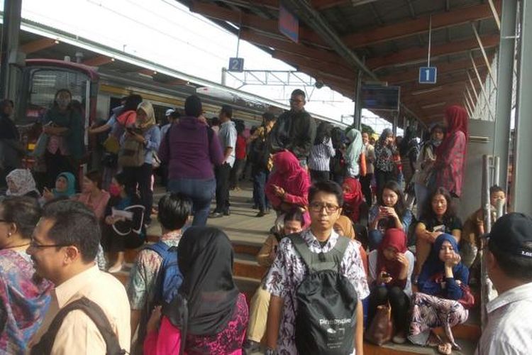 Para calon penumpang KRL commuter line di Stasiun Depok yang memilih duduk di atas tangga peron akibat rangkaian KRL yang tersedia tak kunjung diberangkatkan, Rabu (3/2/2016).