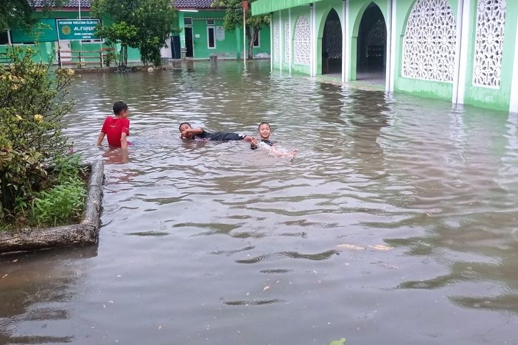 Anak-anak bermain di genangan air banjir di depan halaman Masjid Al Purqon Rangkasbitung usai dilanda hujan deras disertai petir dan angin kencang selama satu jam, Jumat (12/4/2024).