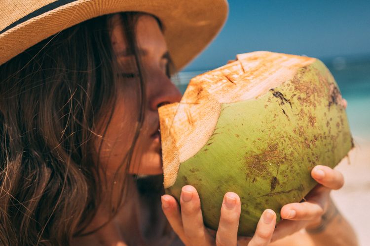 Ilustrasi minum air kelapa. Lebih sehat mana antara air kelapa muda dan air kelapa tua?