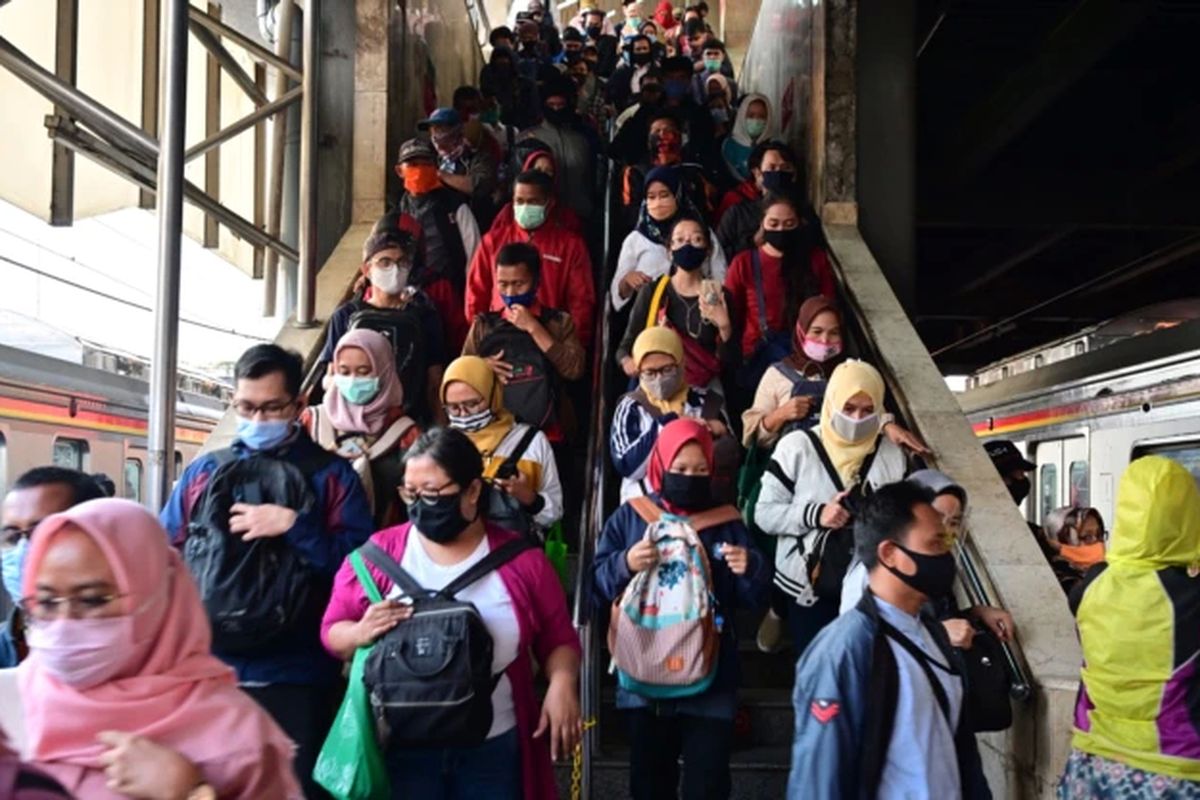 Para komuter yang mengenakan masker wajah berjalan ke peron kereta mereka di stasiun kereta Tanah Abang di Jakarta pada 18 Agustus 2020.