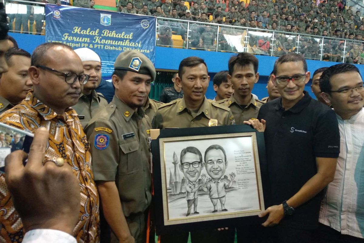 Wakil Gubernur DKI Jakarta Sandiaga Uno menerima hadiah saat menghadiri halalbihalal bersama ratusan pegawai tidak tetap (PTT) Satpol PP dan Dishub DKI Jakarta di GOR PKP, Ciracas, Jakarta Timur, Sabtu (7/7/2018).