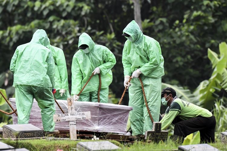 Petugas pemakaman menurunkan peti jenazah pasien COVID-19 di TPU Pondok Ranggon, Jakarta, Senin (30/3/2020). Juru bicara pemerintah untuk penanganan COVID-19 Achmad Yurianto per Senin (30/3/2020) pukul 12.00 WIB menyatakan jumlah pasien positif COVID-19 di Indonesia telah mencapai 1.414  kasus, pasien yang telah dinyatakan sembuh sebanyak 75 orang, sementara kasus kematian bertambah delapan orang dari sebelumnya 114 orang menjadi 122 orang. ANTARA FOTO/Muhammad Adimaja/foc.