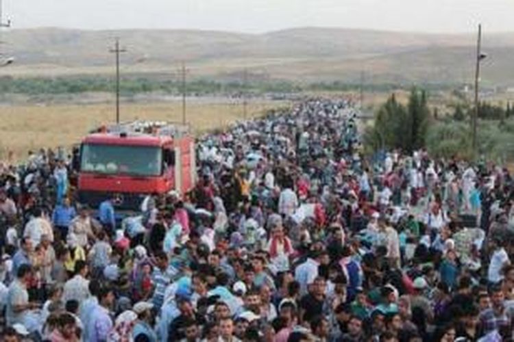 Ribuan pengungsi Suriah berkumpul di tepi Sungai Tigris saat hendak menyeberang ke Irak untuk menghindari kecamuk perang saudara di negeri mereka. Foto ini diambil pada Agustus 2013.