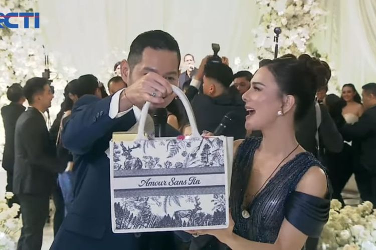 Pembawa acara Evan Sanders (kiri) dan Astrid Tiar (kanan) memperlihatkan tas souvenir pernikahan Amanda Manopo dan Kenny Agustin di The Langham, Jakarta Selatan, Jumat (10/10/2025).