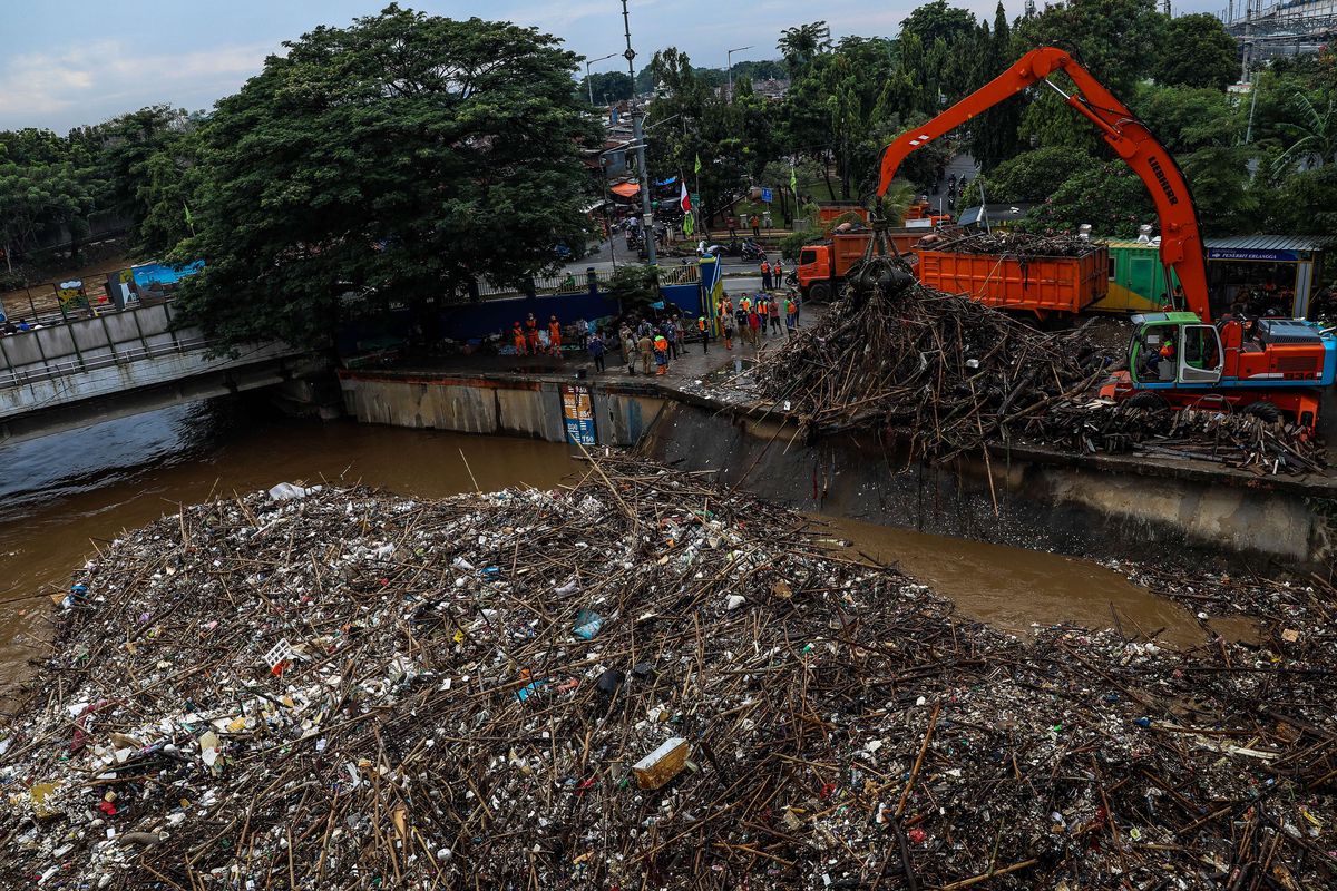 Petugas kebersihan DKI Jakarta mengangkut sampah yang terbawa arus menggunakan alat berat di Pintu Air Manggarai, Jakarta Pusat, Selasa (22/9/2020). Kenaikan muka air di Pintu Air Manggarai diakibatkan oleh hujan yang mengguyur kota Bogor dan Jakarta mulai Senin malam (21/9/2020) selama beberapa jam.