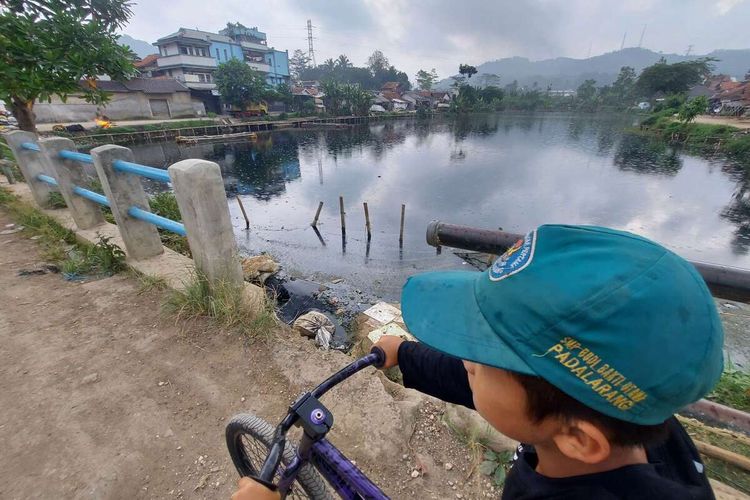 Warga beraktivitas di sekitar Situ Ciburuy, Kabupaten Bandung Barat yang berubah warna menjadi hitam pekat dan bau tak sedap setelah tercemar limbah, Kamis (14/7/2022).