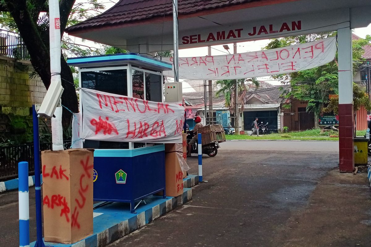 Di sekitar pintu masuk Pasar Madyopuro terlihat terdapat bangunan pos parkir dengan adanya spanduk penolakan bertuliskan 'Menolak E Parkir Harga Mati' pada Kamis (29/12/2022). 