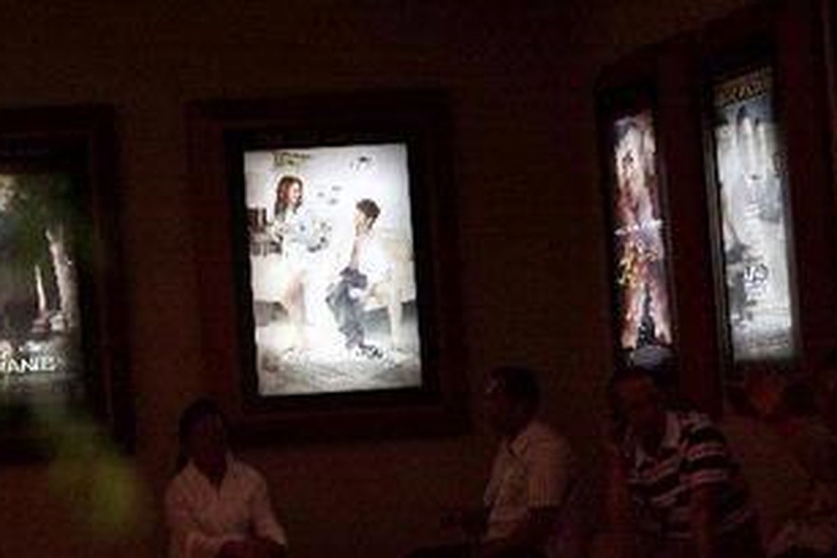 Pengunjung menunggu jadwal pemutaran film dengan latar belakang poster-poster film Hollywood yang tengah diputar di bioskop Metropole XXI, Jakarta Pusat, Sabtu (19/2/2011). Asosiasi produsen film Hollywood, Motion Picture Assosiation of America (MPAA) memutuskan menyetop mendistribusikan film Amerika per 17 Februari 2011 karena keberatan atas bea masuk atas hak distribusi film impor. Kondisi tersebut mengancam bisnis bioskop di tanah air.