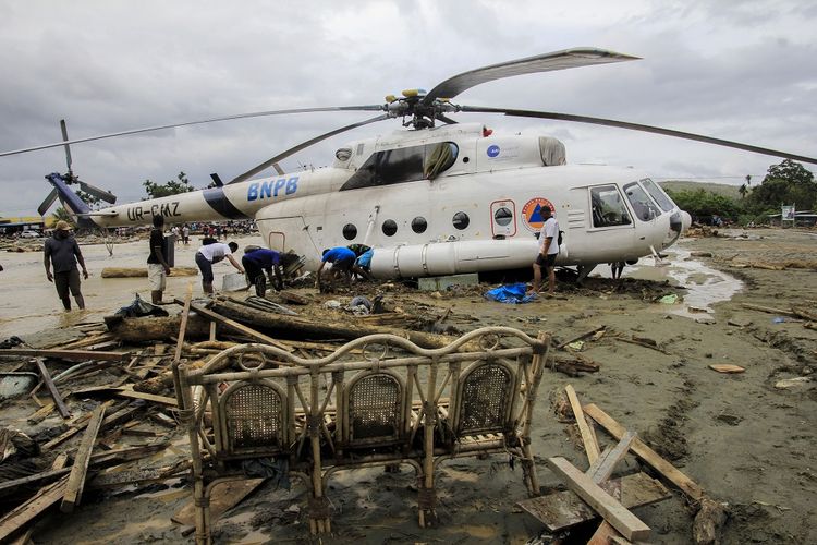 Sejumlah warga berada di dekat helikopter yang bergeser dari tempatnya akibat banjir bandang di Sentani, Kabupaten Jayapura, Papua, Minggu (17/3/2019). Berdasarkan data BNPB, banjir bandang yang terjadi pada Sabtu (16/3) tersebut mengakibatkan 42 tewas. ANTARA FOTO/Gusti Tanati/wpa/ama.