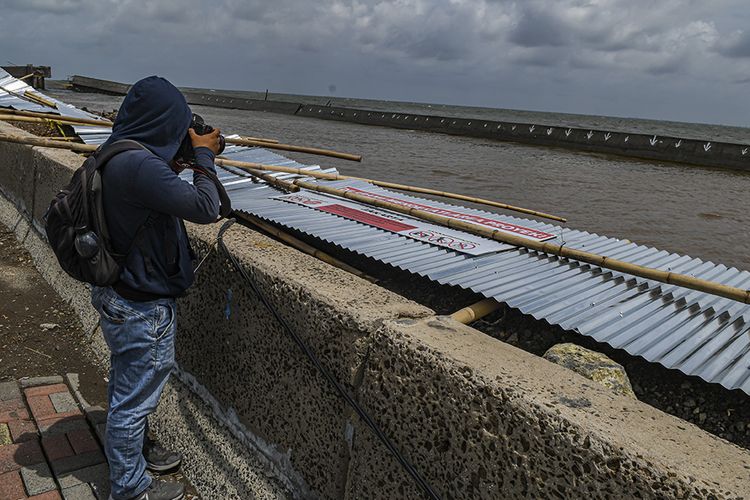 Pewarta foto mengambil gambar Tanggul Proyek Terpadu Pesisir Ibu Kota Negara atau National Capital Integrated Coast yang jebol di Muara Baru, Jakarta, Senin (6/1/2020).  Badan Meteorologi, Klimatologi dan Geofisika (BMKG) memprakirakan daerah pesisir Jakarta Utara akan mengalami air pasang laut (rob) maksimum pada 9 Januari hingga 11 Januari 2020 dan diprakirakan akan memperparah banjir di Jakarta.