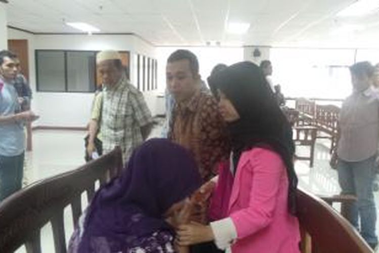 Hendra Saputra tengah menenangkan istrinya (baju ungu) Dewi Nurapipah di Pengadilan Tindak Pidana Korupsi Jakarta, Rabu (23/4/2014).