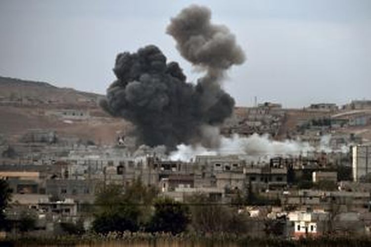 Asap membubung dari kota Kobani, Suriah setelah serangan udara koalisi pimpinan AS menyerang beberapa posisi ISIS di kota tersebut. Pemandangan ini terlihat jelas dari kota Mursipitnar, Turki.
