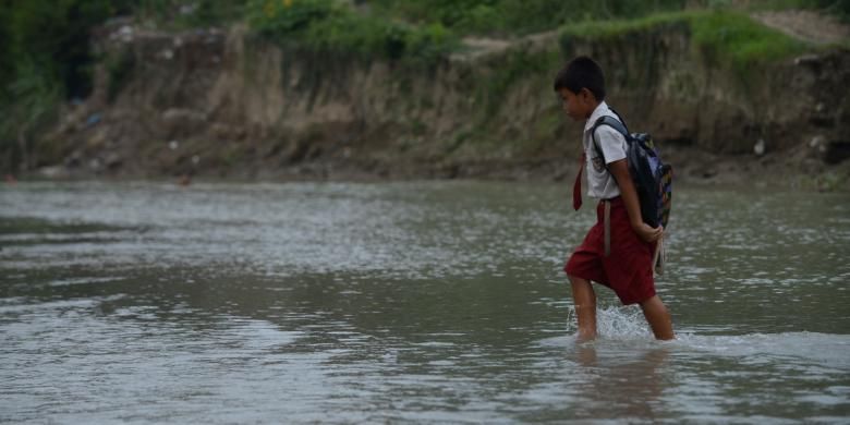 Siswa menyeberangi sungai untuk kembali ke rumah setelah masuk sekolah pada hari pertama di Desa Jragung, Kecamatan Karangawen, Kabupaten Demak, Jawa Tengah, Senin (15/7/2013)