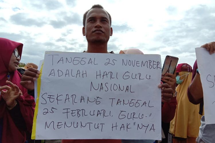 Seorang guru sedang memegang panflet saat aksi demo yang berlangsung di Lapangan Timika Indah, Senin (25/2/2019)