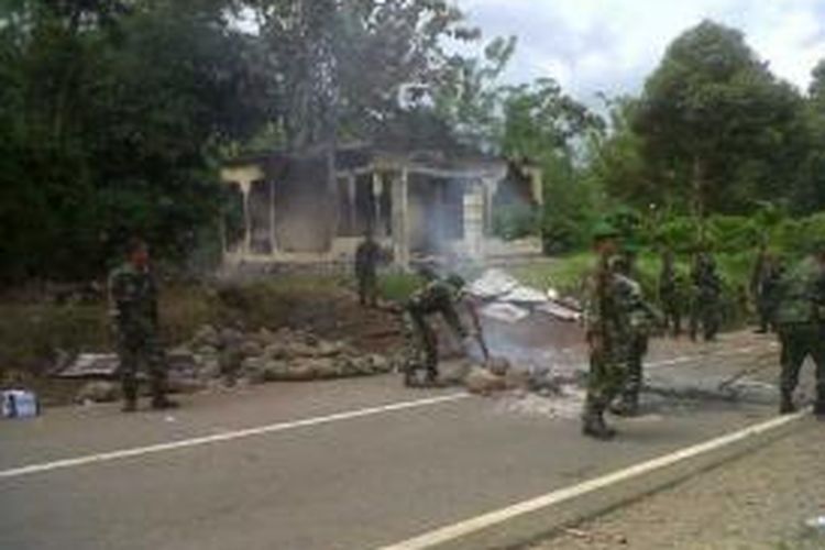 Anggota TNI membersihkan blokade jalan di depan pos polisi yang dirusak massa