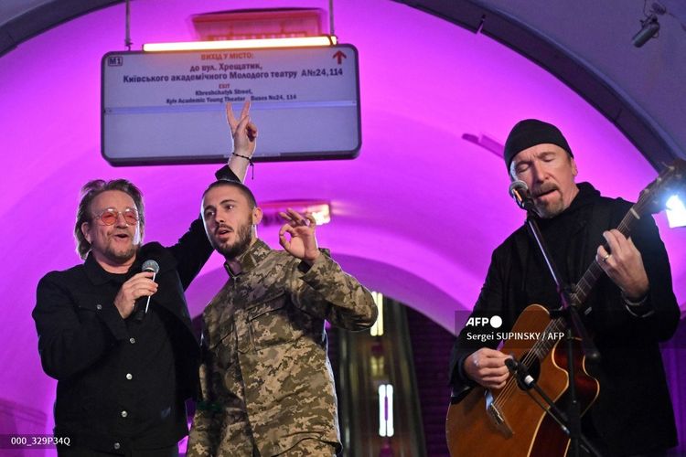Dua personel band U2, yakni vokalis  Paul David Hewson atau Bono (kiri) dan gitaris David Howell Evans atau The Edge (kanan), tampil bersama penyanyi militer Ukraina Taras Topolia (tengah) di stasiun bawah tanah yang kini menjadi tempat perlindungan di Kyiv, Ukraina, Minggu (8/5/2022).