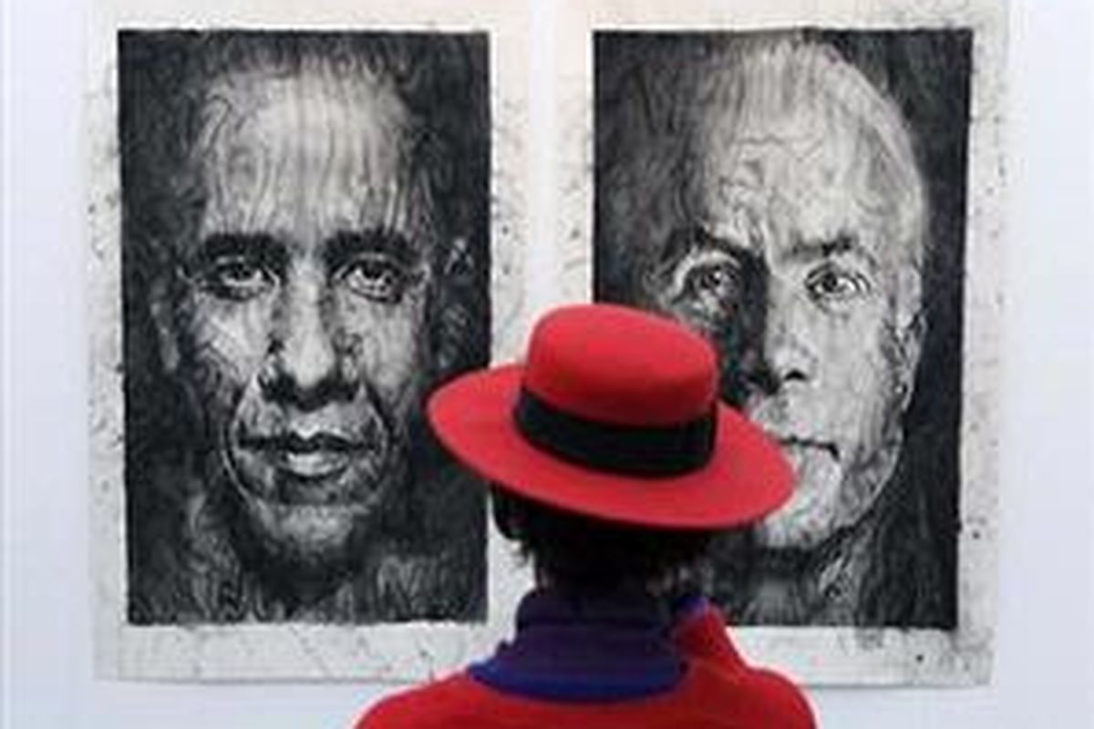 Seorang wanita mengamati lukisan raksasa calon presiden AS, Barack Obama (kiri) dan John McCain saat mengunjungi pameran seni kontemporer internasional 'Grand Palais' di Paris, 24 Oktober 2008. 