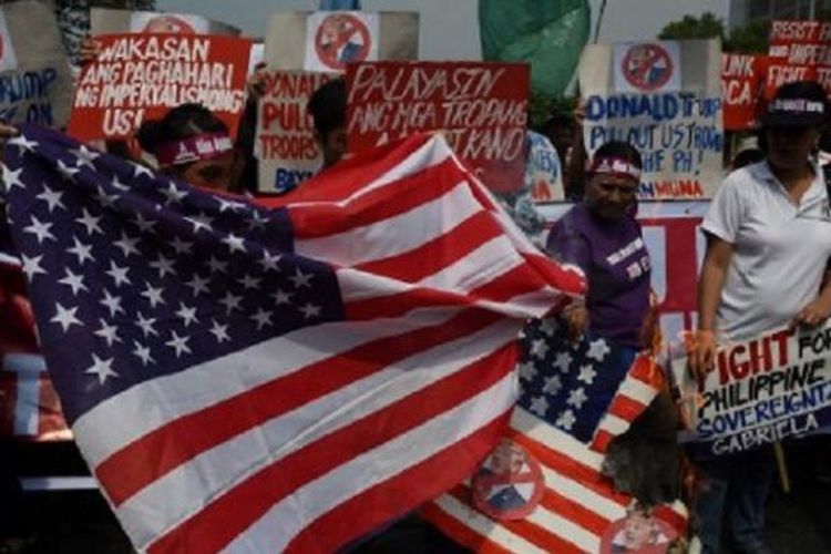 Pendemo membakar bendera Amerika Serikat dalam unjuk rasa di depan Kantor Kedutaan Besar AS di Manila, Jumat (20/1/2017).  