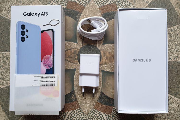 Isi kotak kemasan Samsung Galaxy A13 yang terdiri dari buku panduan singkat, nomor IMEI, kepala charger dengan keluaran daya 15 watt, konektor charger USB type A ke USB type C, dan ejektor, Tidak ada softcase dan earphone di dalam kotak kemasan.