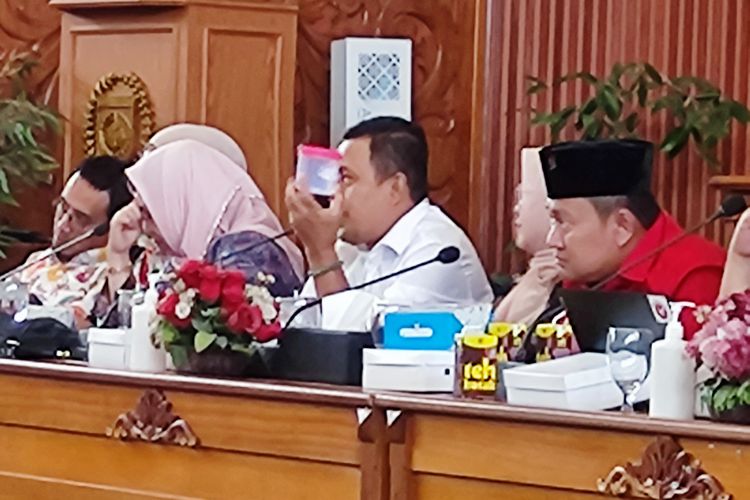 Anggota DPRD Depok Babai Suhaimi menunjukkan toples wadah menu PMT, di ruang rapat paripurna DPRD Depok, Jumat (17/11/2023). 