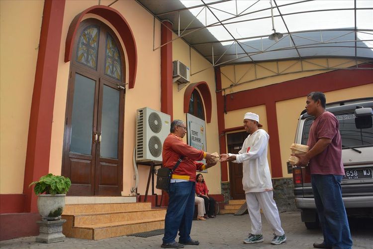 Sekretaris Gereja Kristen Jawi Wetan (GKJW) Jombang, Bambang Sujianto (kiri), saat menerima paket daging kurban dari Sulis Setia (tengah), Ketua RT 01 RW 01, Kelurahan Kaliwungu, Kecamatan Jombang, Kabupaten Jombang, Jawa Timur, Minggu (11/8/2019).