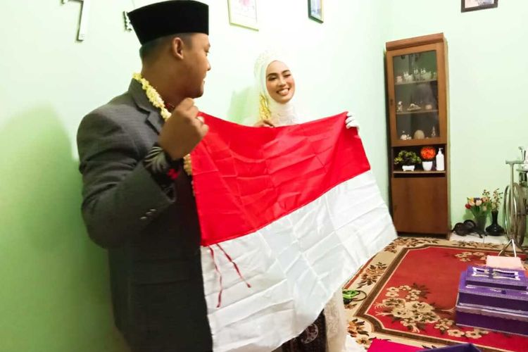 Pasangan mempelai M Arif Al Fajar (29) dan Tsaniyah Faidah (25) membentangkan maskawin bendera merah putih di hadapan tamu undangan di rumah mempelai wanita di Jalan Sasak, Cilodong, Depok, Sabtu (8/8/2020).