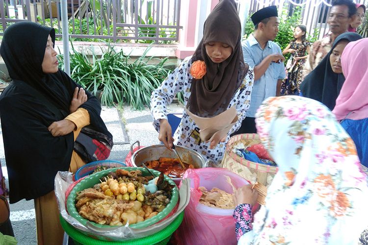 Salah seorang pedagang melayani para pengunjung dalam Festival Sego Boranan di Lamongan, Jatim, Sabtu (26/5/2018).