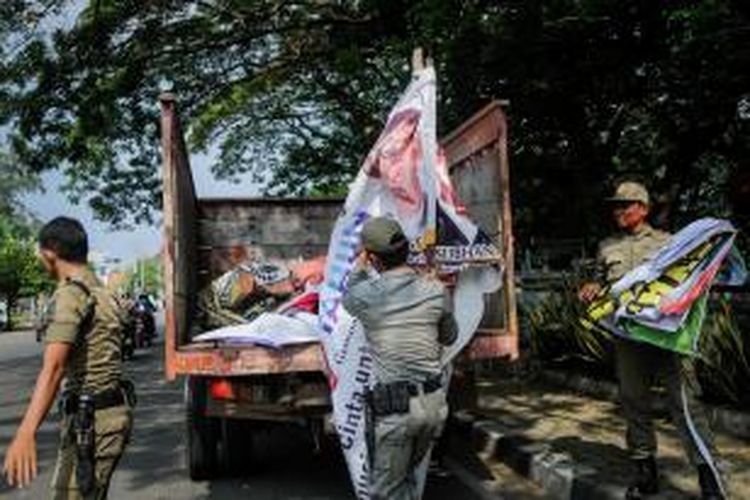 Petugas Satpol PP mencopot alat peraga kampanye milik calon anggota legislatif (caleg) yang dipasang di seputaran Simpang Jam, Kota Banda Aceh, Selasa (21/1/2014), Keindahan kota dan kenyamanan warga terganggu akibat banyaknya caleg yang melanggar aturan pemasangan alat peraga kampanye jelang pemilu 9 April mendatang. SERAMBI/M ANSHAR