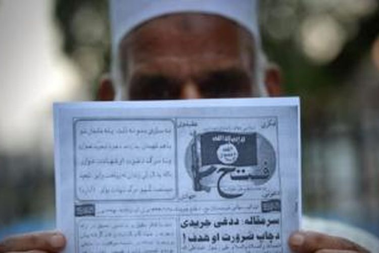 Seorang pria Pakistan memegang pamflet yang diduga disebarkan oleh militan Negara Islam (ISIS)di Peshawar, barat laut Pakistan. 