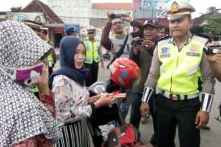 Salah seorang pengendara motor mendapat hadiah cokelat dari polisi saat razia simpatik di kawasan pecinan, Demak, yang digelar Satlantas Polres Demak dalam rangka memperingati Kesaktian Pancasila,  Jumat (30/9/2016).