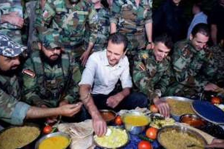 Dalam salah satu foto yang dirilis pemerintah Suriah terlihat Presiden Bashar al-Assad tengah berbuka puasa bersama para prajuritnya di salah satu garis depan tak jauh dari ibu kota Damaskus.