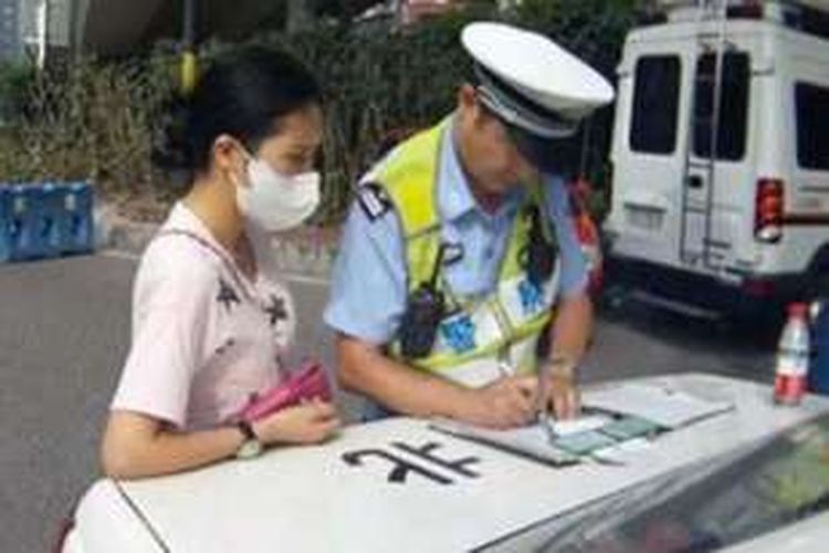 Petugas polisi lalu lintas di kota Chongqing, China menilang seorang perempuan muda yang ketahuan mengemudikan mobil sambil menyusui bayinya.