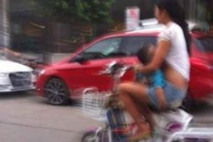 Seorang ibu muda di China melakukan aksi berbahaya ketika dia menyusui bayinya sambil melaju di atas sepeda motor.