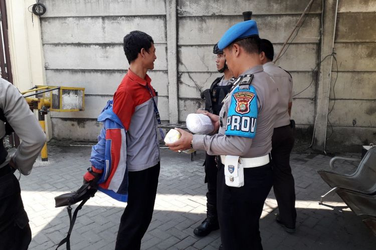 Polisi memeriksa barang bawaan seorang pengunjung di Mapolres Pelabuhan Tanjung Priok, Senin (15/4/2018).