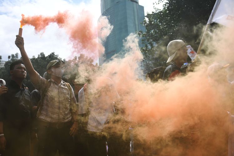 Pengunjuk rasa menyalakan flare saat aksi di gedung KPK, Jakarta, Selasa (11/4/2023). Unjuk rasa menuntut mundurnya Ketua KPK Firli Bahuri itu berlangsung ricuh serta ditandai dengan pelemparan tikus dan telur ke arah gedung KPK.