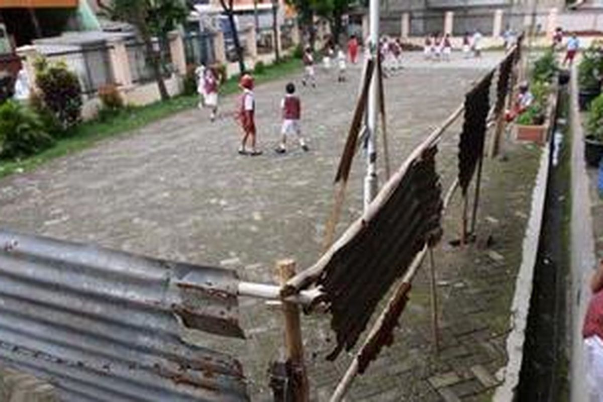 Siswa SDN Kembangan Utara 2 Petang, Jakarta Barat, bermain di sekitar pagar kawat berduri dan seng yang terdapat di halaman sekolah, Senin (10/1/2011). Kawat berduri dan seng tersebut dipasang oleh ahli waris tanah untuk menagih uang pembayaran tanah dan pekerjaan sebagai PNS yang telah dijanjikan oleh pemerintah daerah. Pemagaran halaman tersebut sangat mengganggu kegiatan di sekolah itu. 