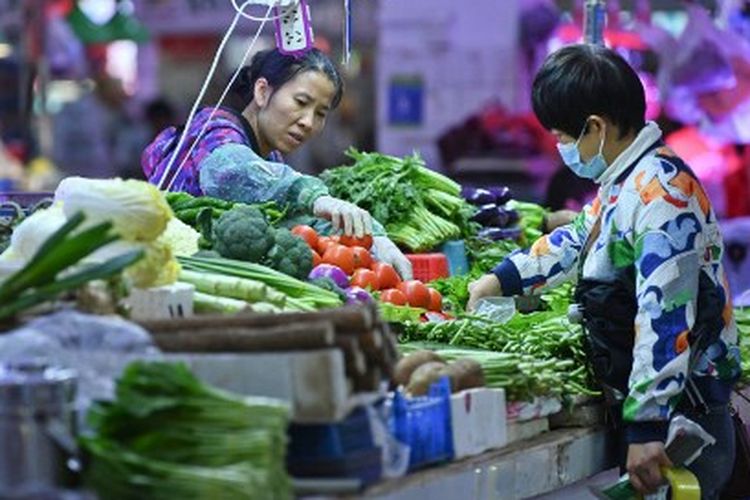 Foto yang diambil pada 1 November 2021 ini menunjukkan seorang penduduk membeli sayuran di sebuah pasar di Nanning, di wilayah Guangxi selatan China.