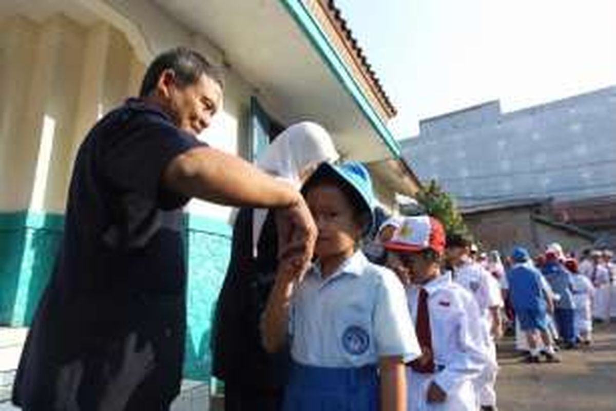 Guru bersalaman dengan murid baru kelas I saat hari pertama masuk sekolah, di SD Negeri Palmerah 07 Pagi, Palmerah Utara, Jakarta, Senin (18/7/2016). Sebanyak 65 murid baru di SDN Palmerah 07 Pagi nampak diantar oleh orangtua pada hari pertama tahun ajaran baru 2016/2017.

