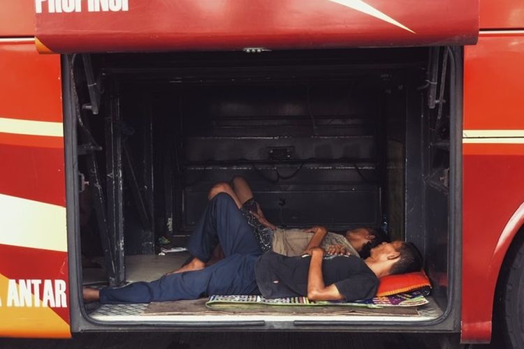 Seorang sopir dan kondektur terlelap di bagasi bus antar kota antar provinsi (AKAP) yang berada di Terminal Kalideres, Jakarta Barat, Jumat (6/5/2022). 