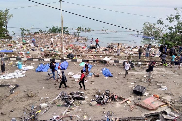 Warga berjalan melewati jenazah korban yang meninggal karena tsunami menghantam pesisir Kota Palu, Sabtu (29/9/2018). Hari Jumat kemarin, gempa dan tsunami mengguncang wilayah Sulawesi Tengah, terutama di Kabupaten Donggala dan Kota Palu. Sampai dengan hari Sabtu pukul 13.00, jumlah korban meninggal hanya di Kota Palu saja sementara mencapai 384 orang.