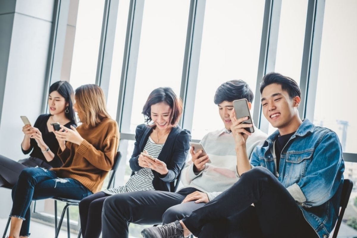 Ilustrasi sekumpulan anak muda yang sedang memainkan media sosial menggunakan smartphone.