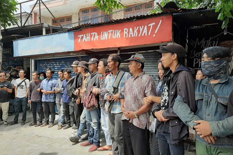 Massa aksi saat berdiri berjajar dan saling bergandengan didepan lapak PKL di jalan Brigjend Katamso, Kecamatan Gondomanan, Kota Yogyakarta yang akan dieksekusi oleh petugas PN Kota Yogyakarta.