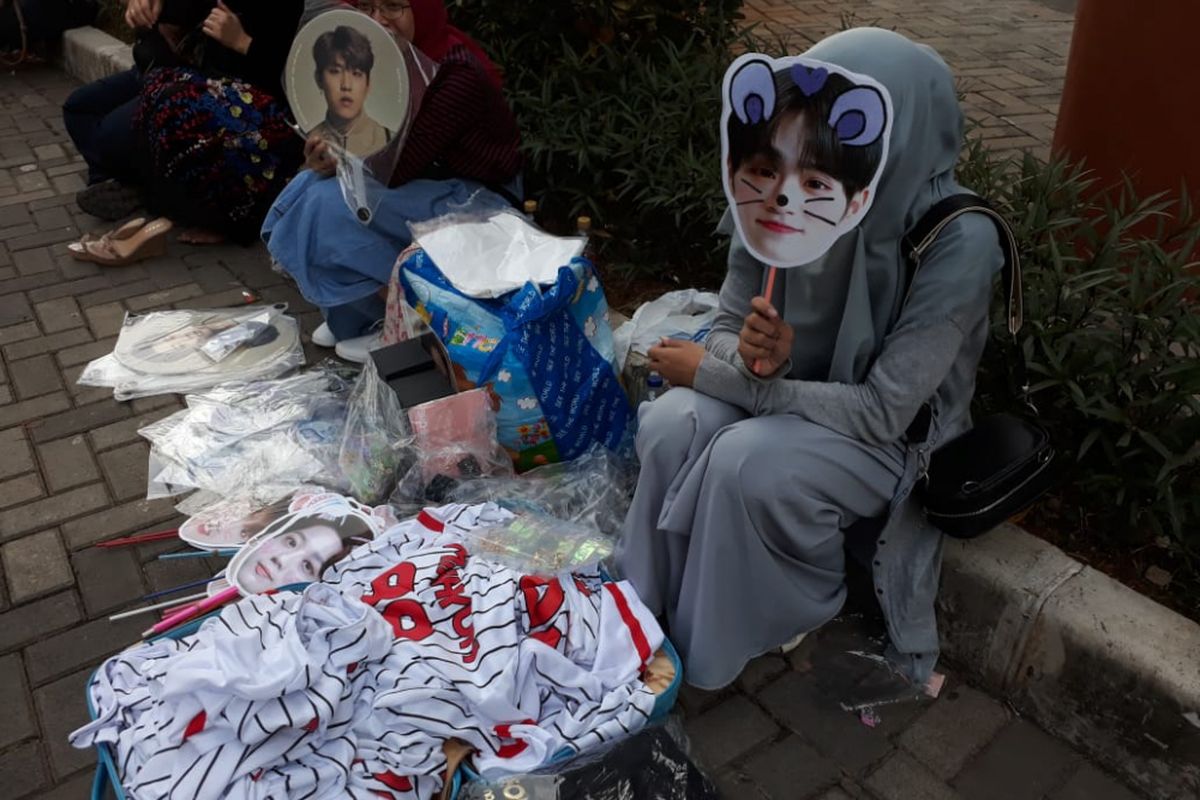 Seorang penjual merchandise Wanna One menggelar barang dagangan di lokasi konser boyband asal Korea Selatan tersebut menjelang konser One: The World di Indonesia Convention Exhibition, BSD City, Tangerang, Minggu (15/7/2017).