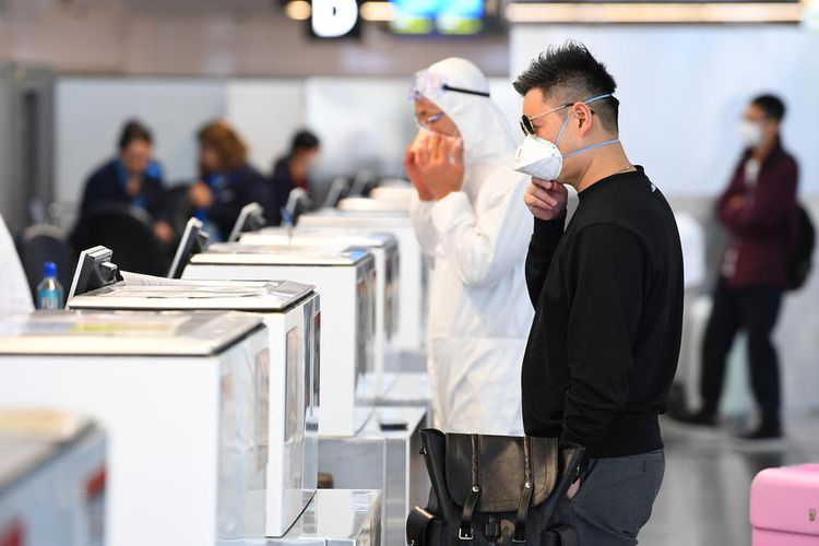 Orang-orang yang memakai alat pelindung diri berdiri di checkin bagasi di dalam terminal keberangkatan internasional di Bandara Melbourne Tullamarine, di Melbourne, Australia, 13 Maret 2020.  EPA-EFE/JAMES ROSS AUSTRALIA AND NEW ZEALAND OUT